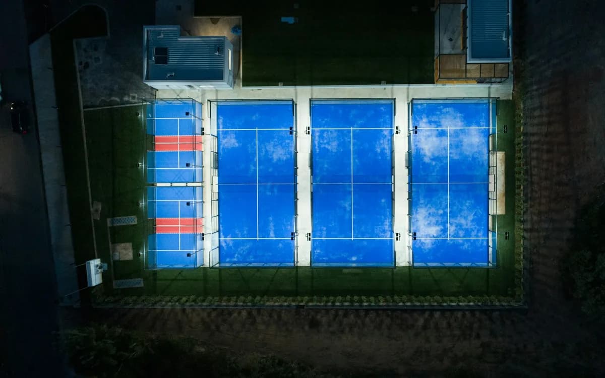 Beleuchtete Padel-Courts aus der Luft bei Nacht